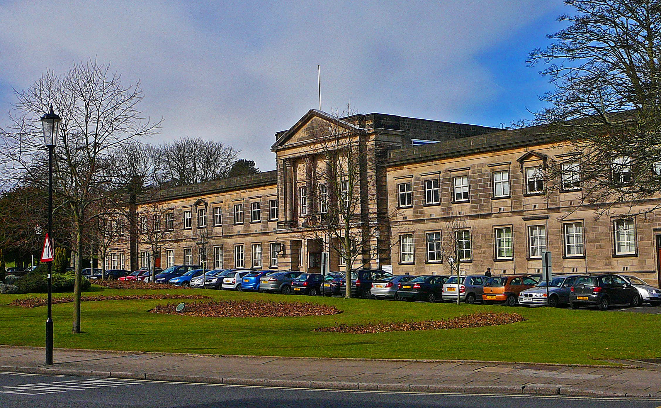 a building sits in the distance surrounded by parked cars