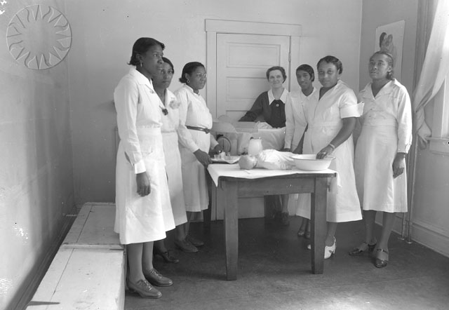 a group of nurses are standing around a table