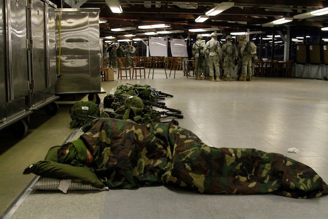 military sleeping bags line the floor next to the luggage carts