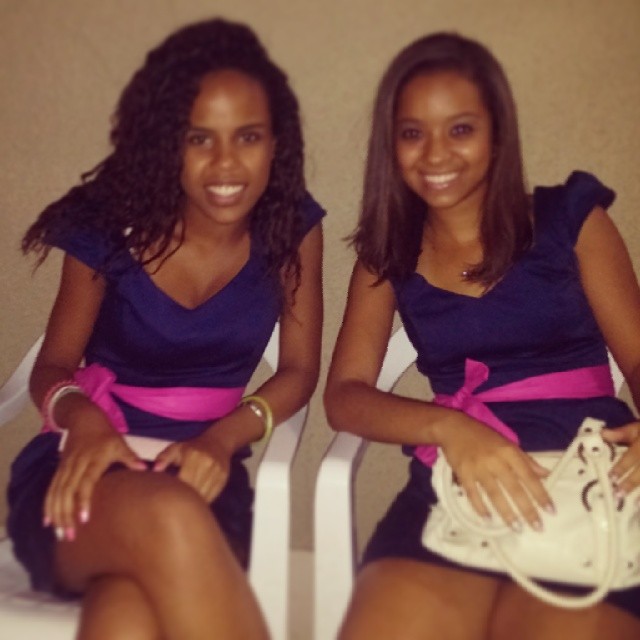 two young women are sitting and smiling while wearing matching outfits