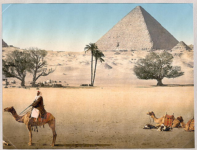 a group of people sitting on camels in front of some pyramids