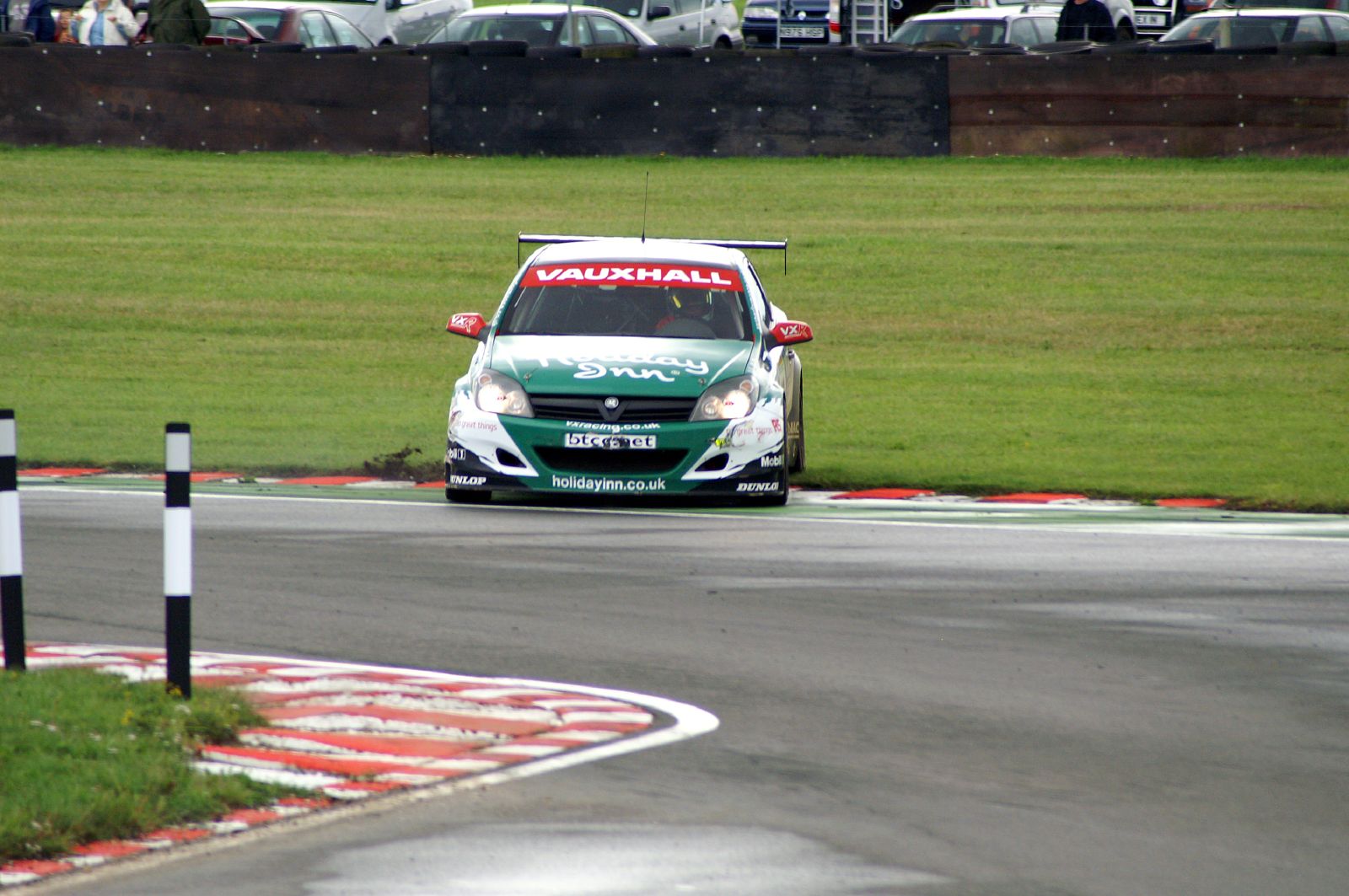 a small car racing around a turn on a wet track