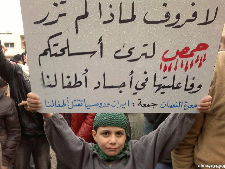 a boy holds a sign in arabic writing