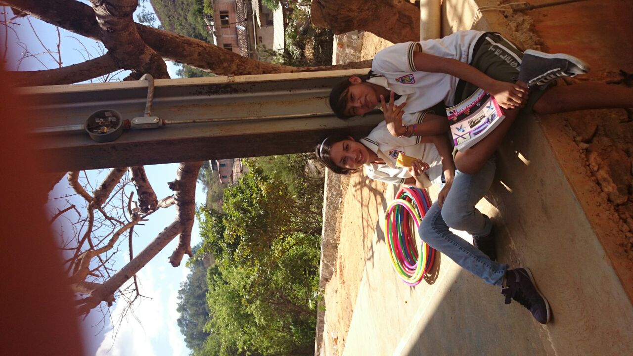 two young people sitting on a wall near a tree