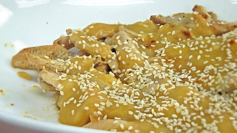 a meal with sesame seeds and chicken in a white bowl