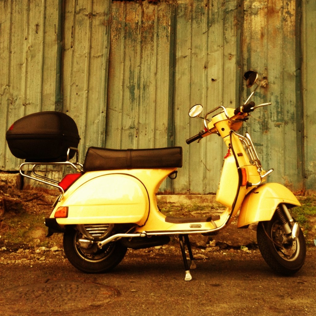 a yellow scooter parked in front of a wooden building