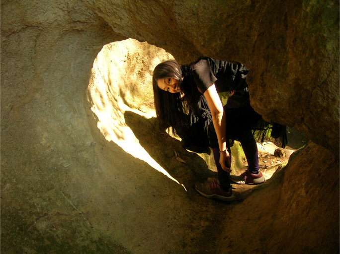 a woman sitting in a small cave in the desert