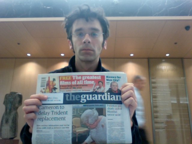 a man reading the paper with a mirror in the background