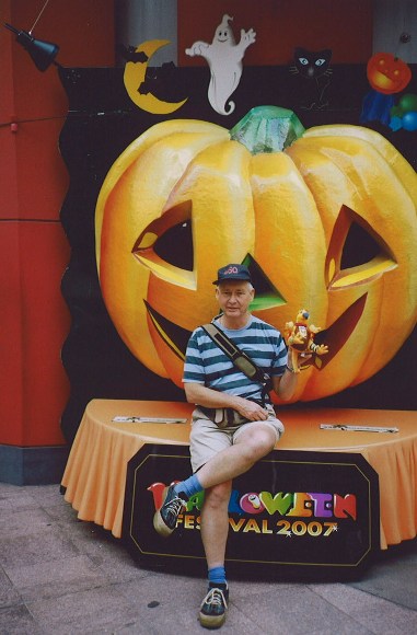 a man sitting next to a pumpkin on top of a table