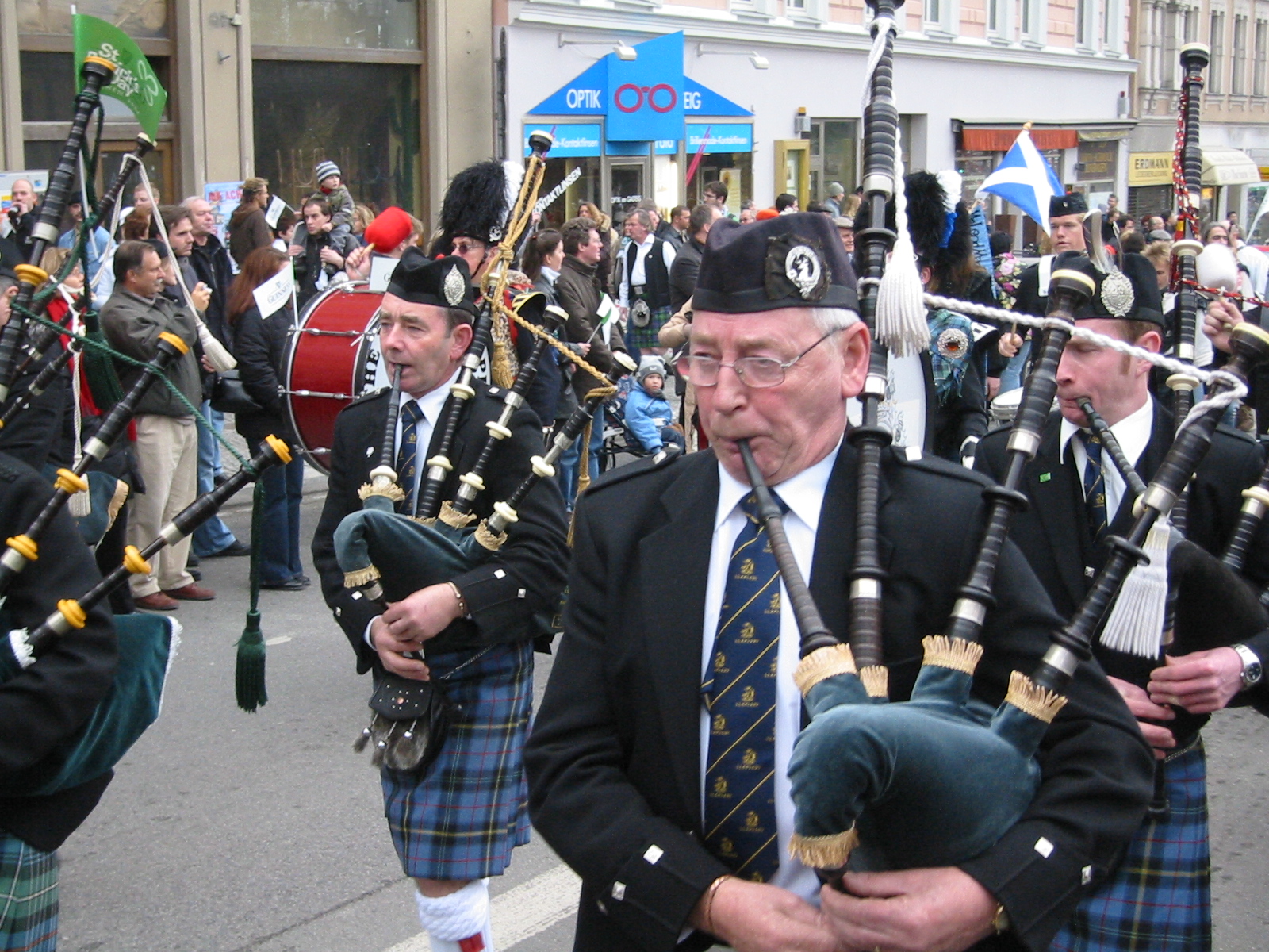 men wearing kilts and playing their bags marching down the street