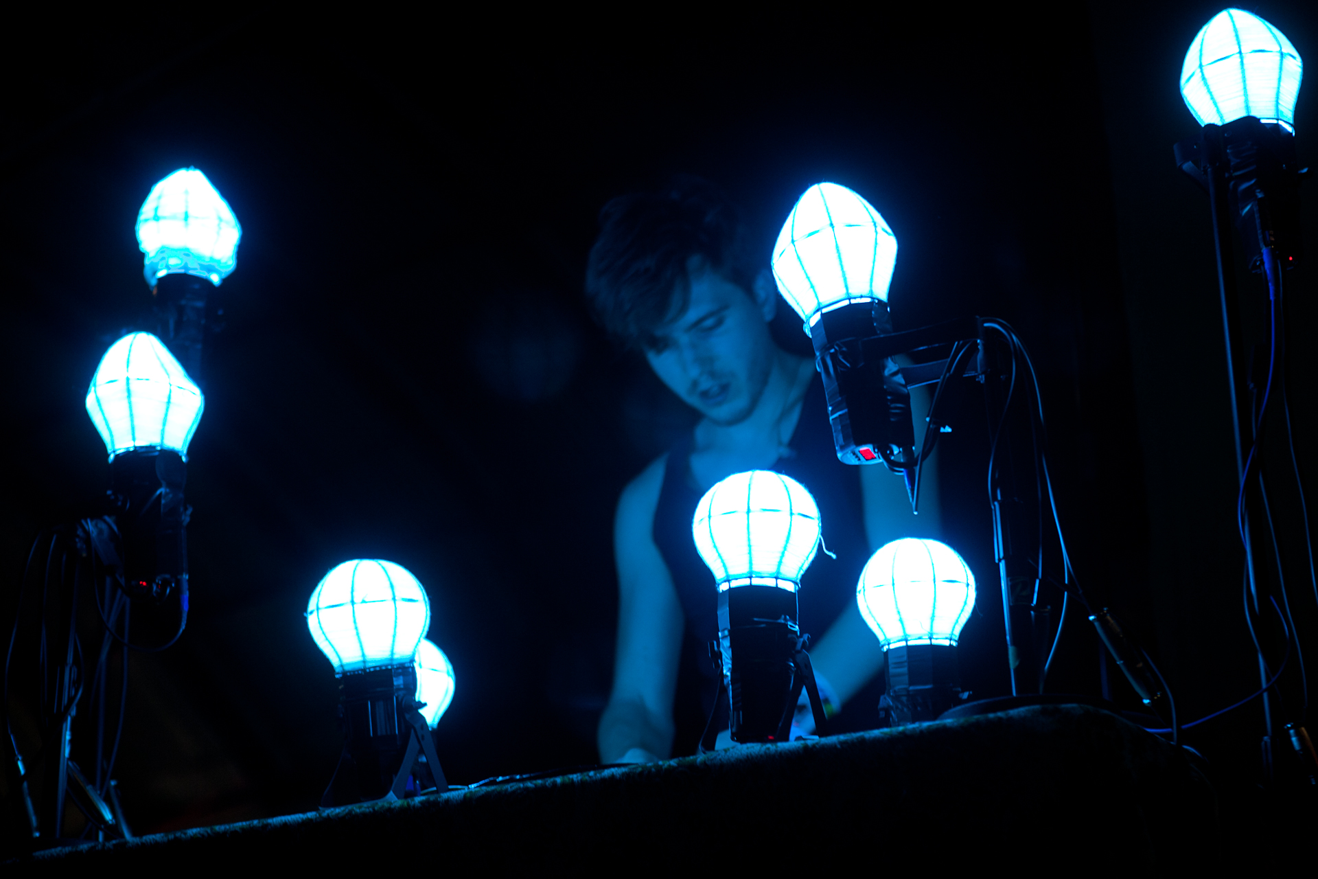 a boy is looking at the light bulbs in the dark