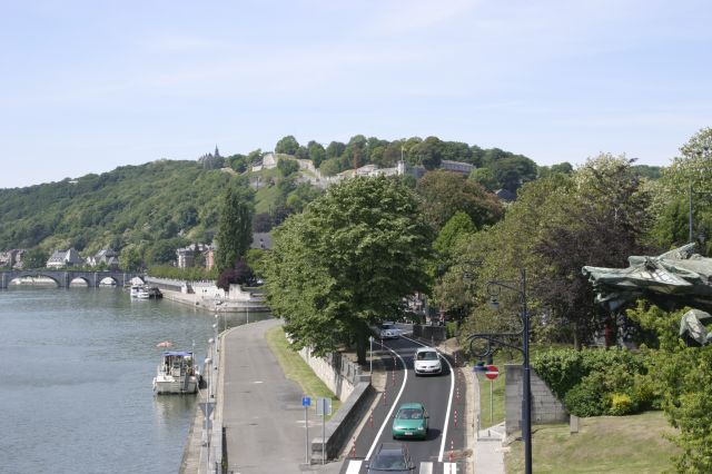 a street and river with cars driving near a bridge