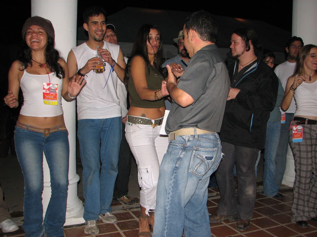 group of people holding drinks and dancing around in a public place