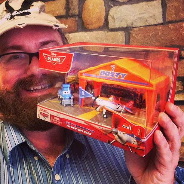 man with pirate hat holding up two play sets of planes