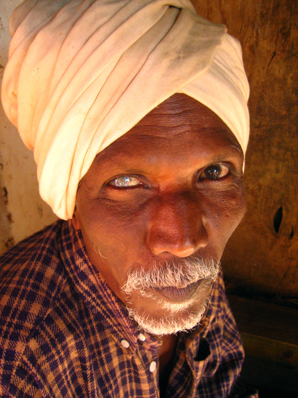 an old man in a turban staring intently at the camera