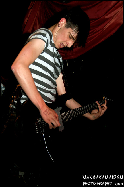 man playing an electric guitar in front of red curtain