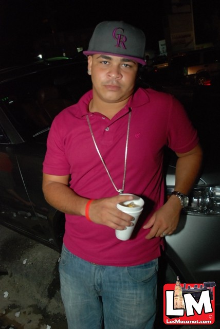 a person in a pink shirt standing by a car