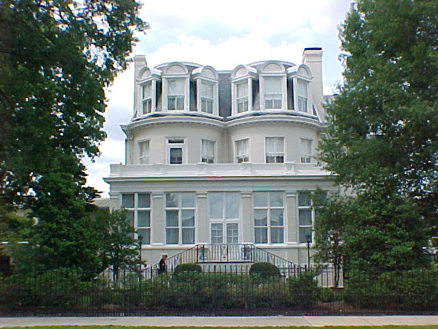 an old white house is pictured through the trees
