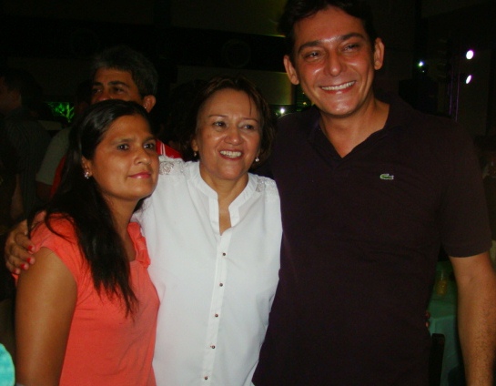 a smiling man is standing between two women