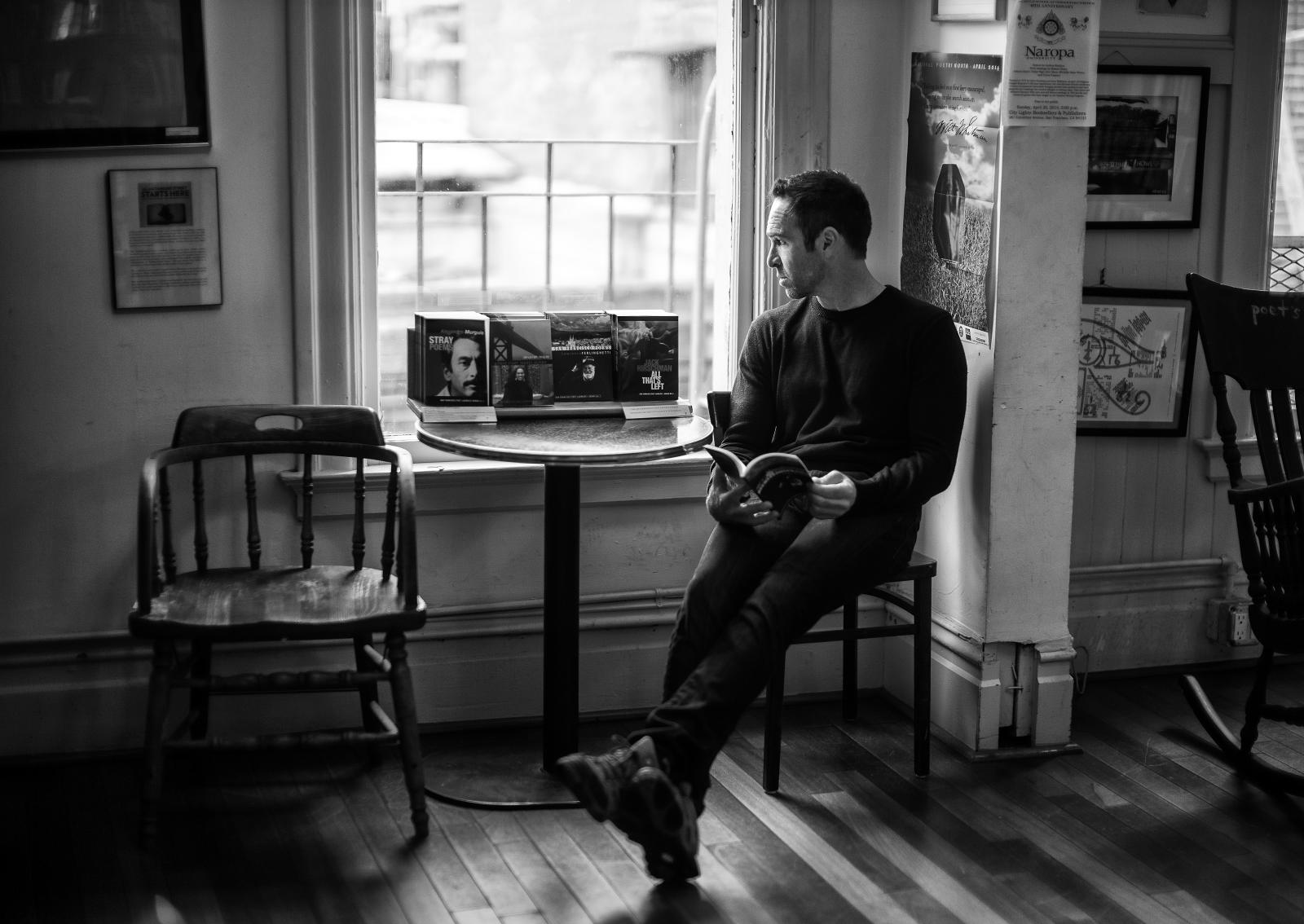 a man sitting on top of a wooden bench near a window