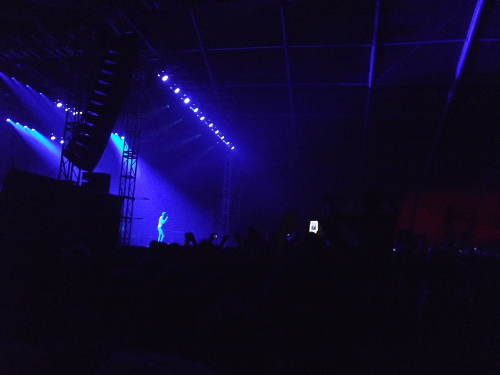 dark po of stage lighting and people on cell phones