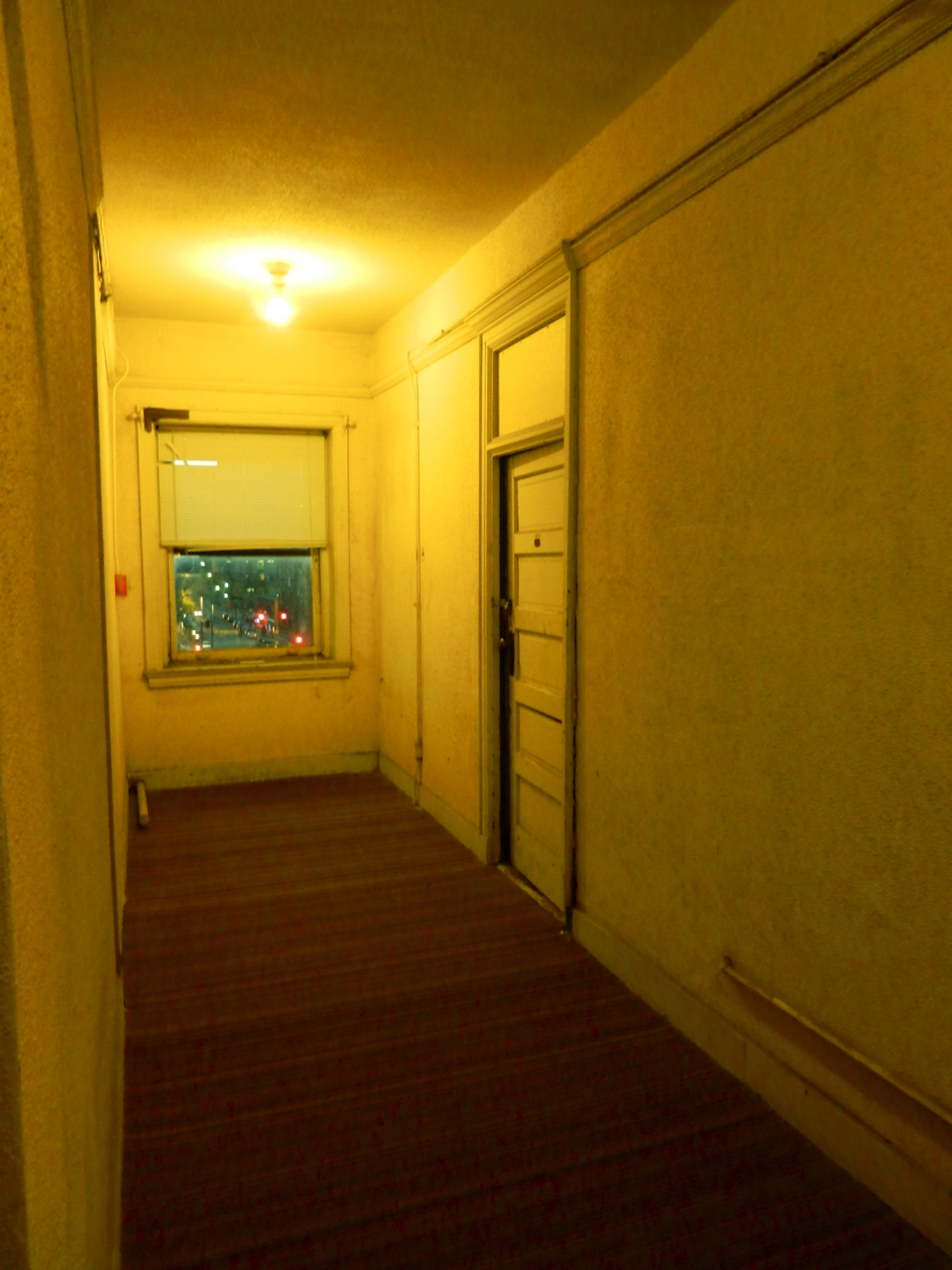 a long hallway leads to a small window on the opposite side