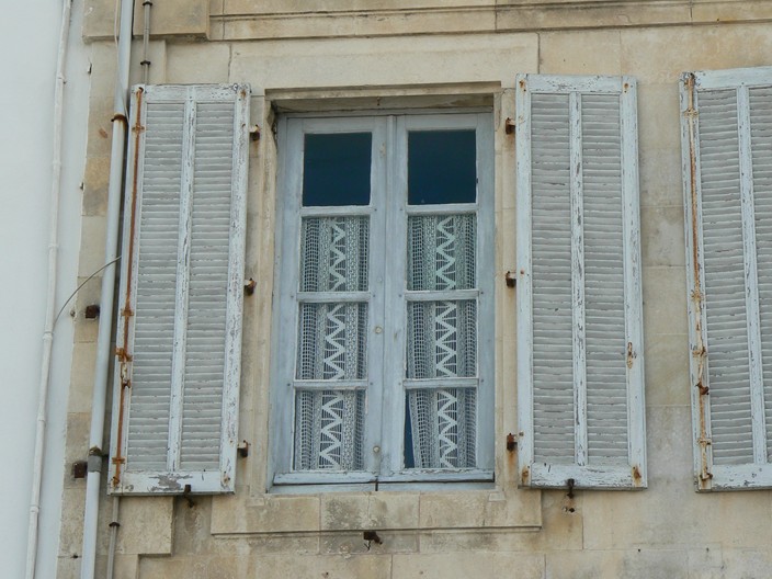 two old windows with white shutters on an exterior building