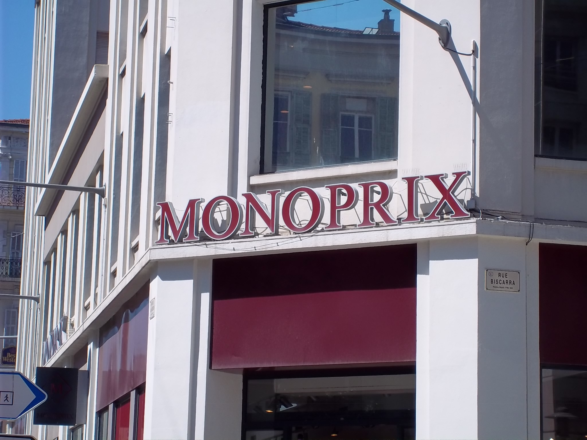 a red awning on the side of a white building