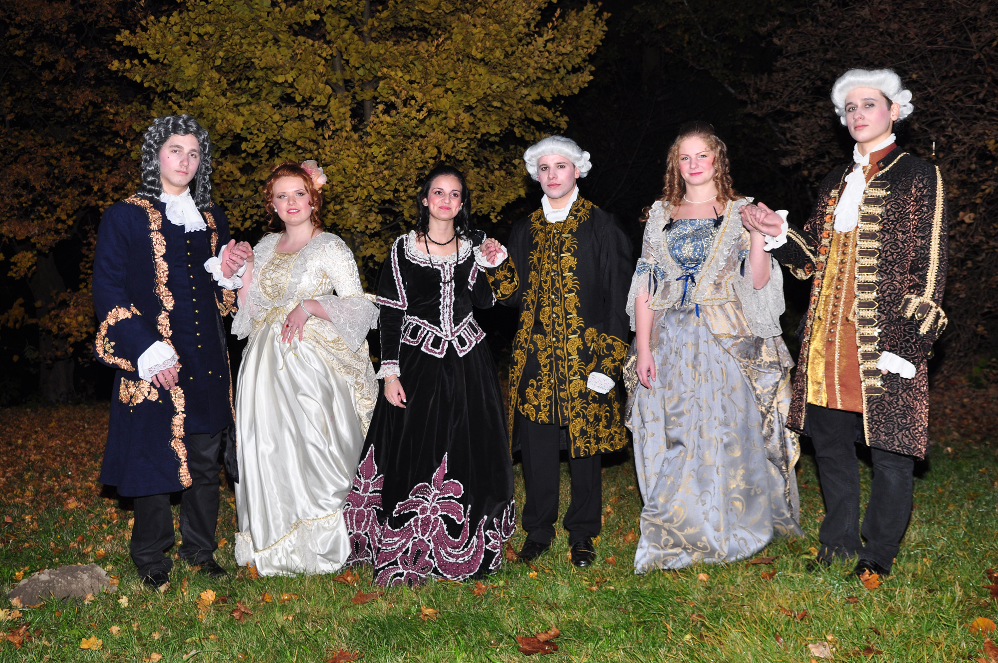 several women in renaissance costumes standing on grass