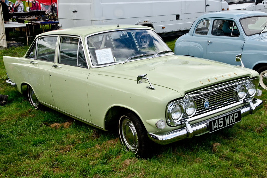 two old cars parked next to each other in a field