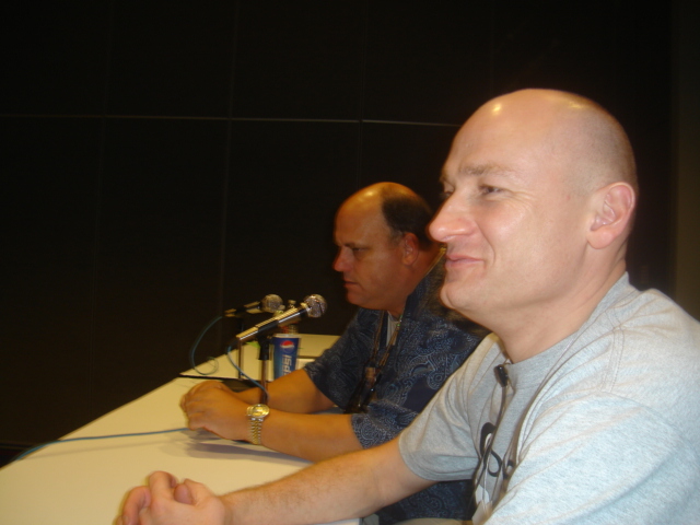 two men sitting at a table in front of microphones