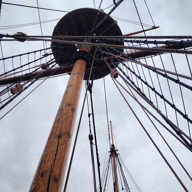 a large mast of a tall boat with ropes around it