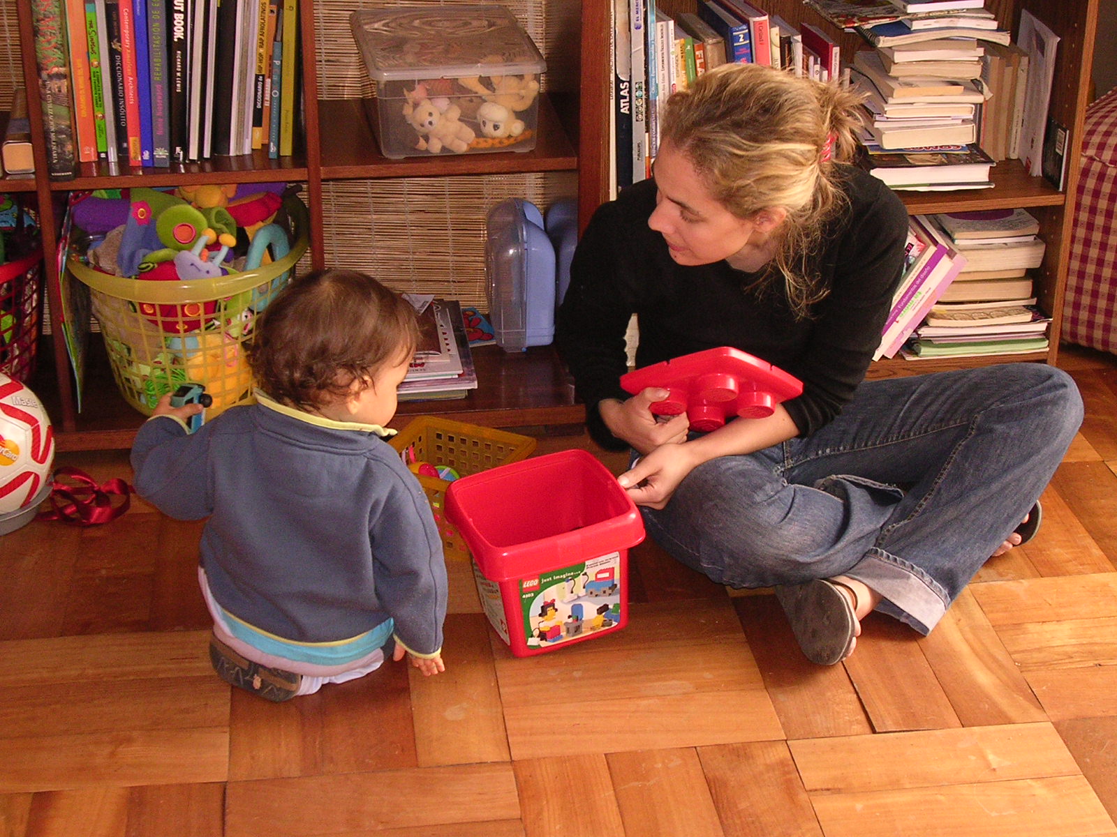 a woman sitting next to a toddler with a red box on its lap