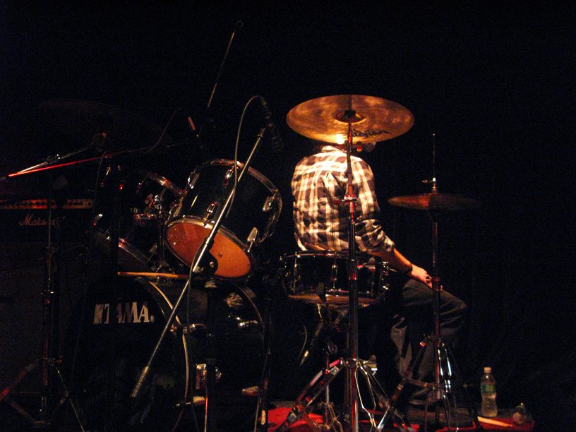 drummer sitting behind the drum kit on stage