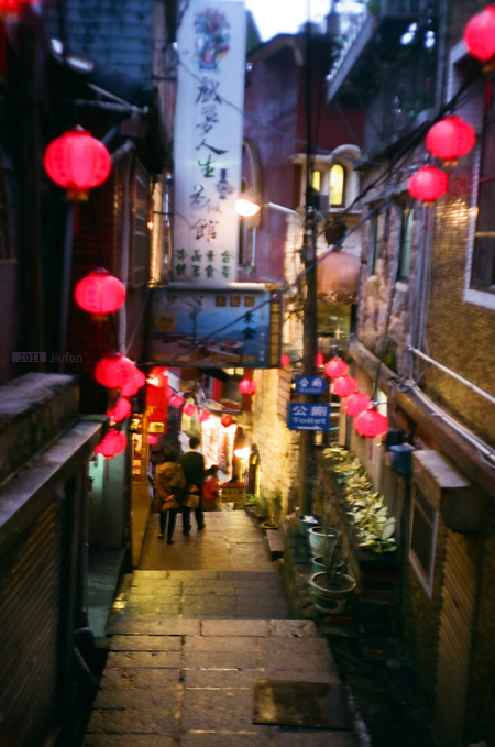 a narrow street with small lit up signs at night