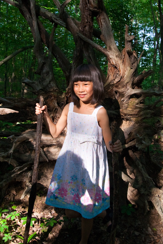 a girl with an stick standing in the woods