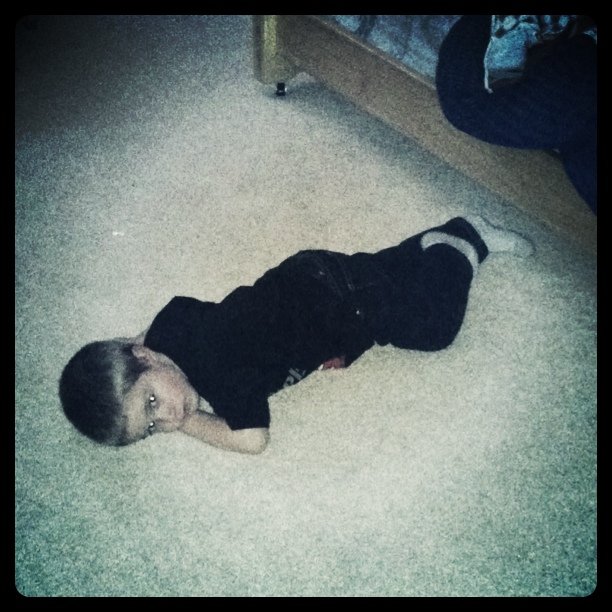 a boy laying on the floor with his head on his belly