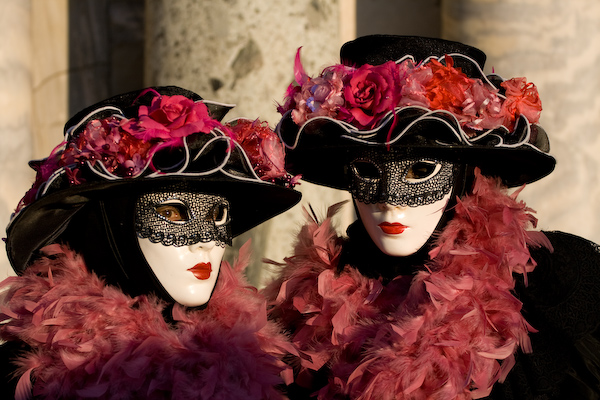 two white masks dressed in costumes of different colors