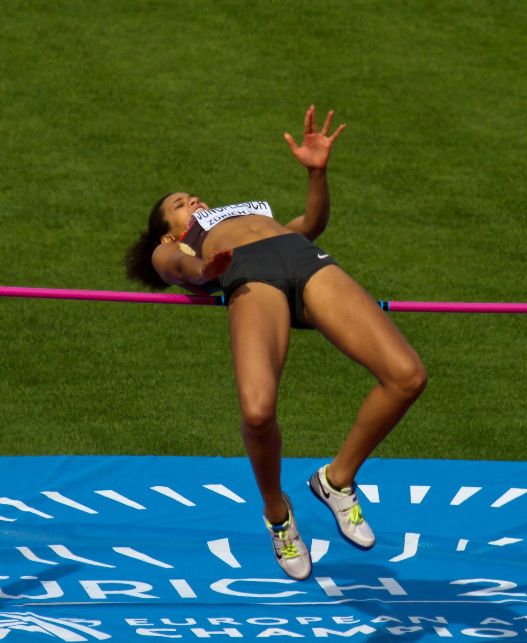 a female athlete wearing black has her hands in the air