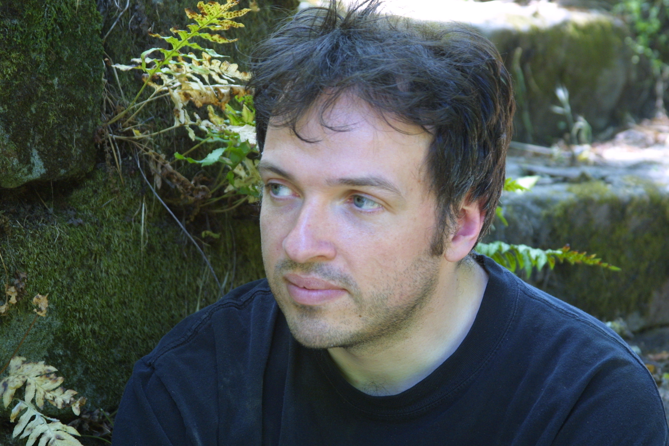 man sitting on the rocks with blue eyes staring straight ahead