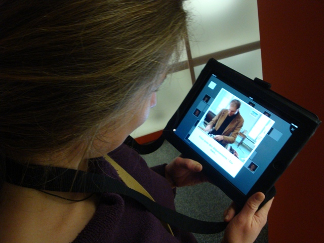 a girl holding a tablet displaying a video on her cell phone