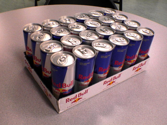 a pile of red bull beer sitting on top of a white table