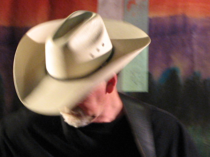 a man wearing a hat that is standing in front of a wall