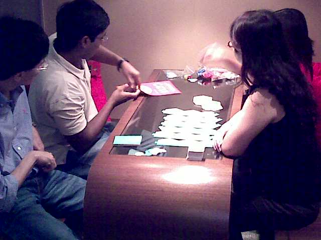 four people sitting at a table playing with a game