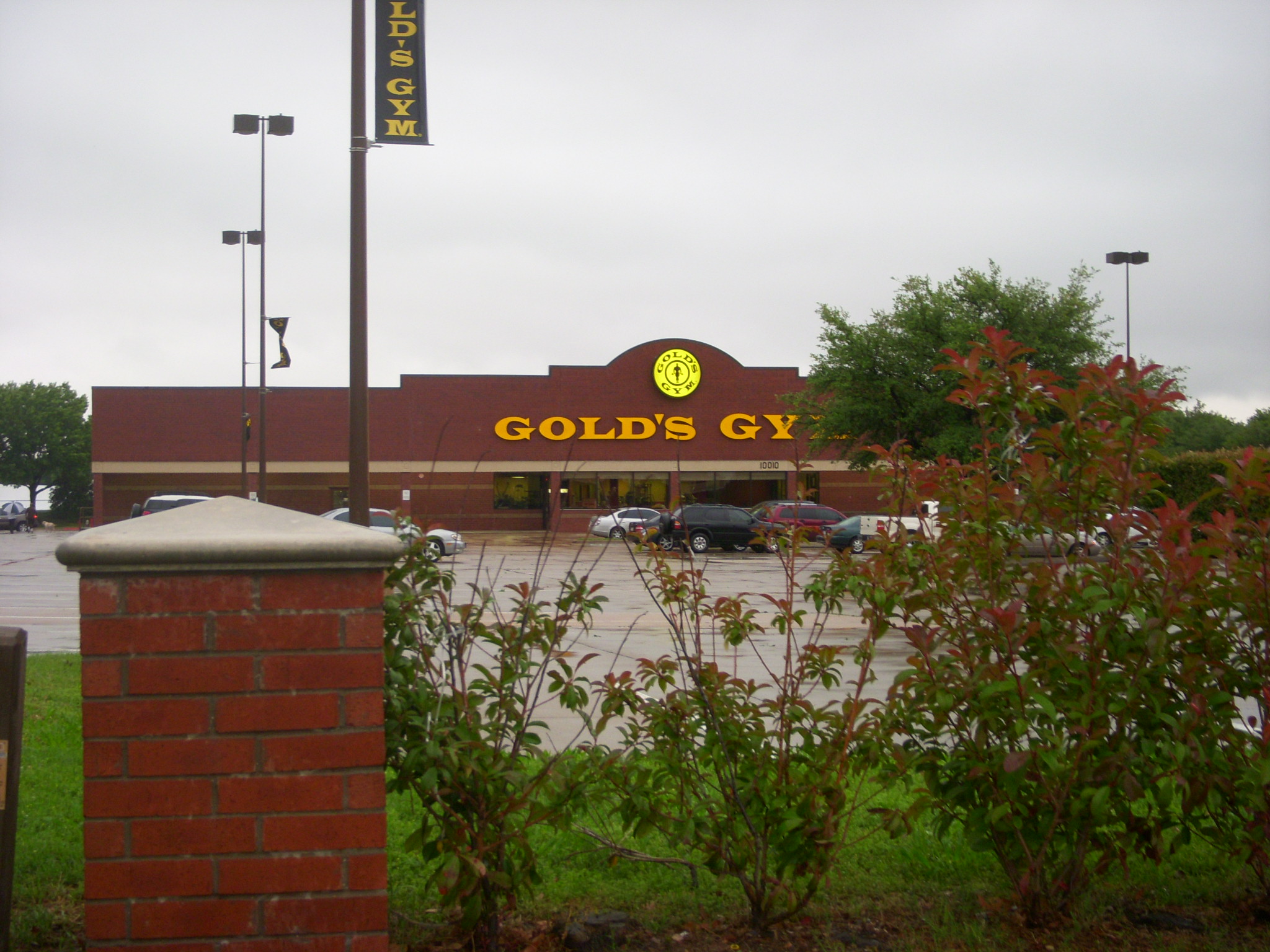 the entrance to golds gym with bushes growing around