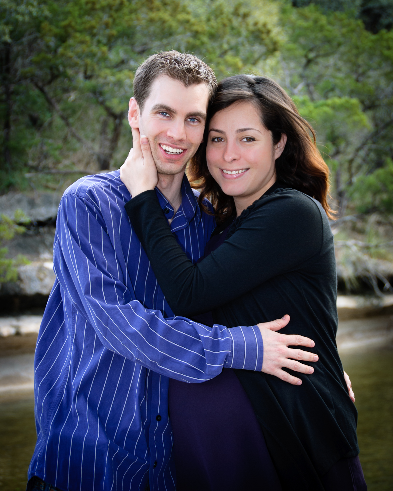 a couple hugging each other in front of a river