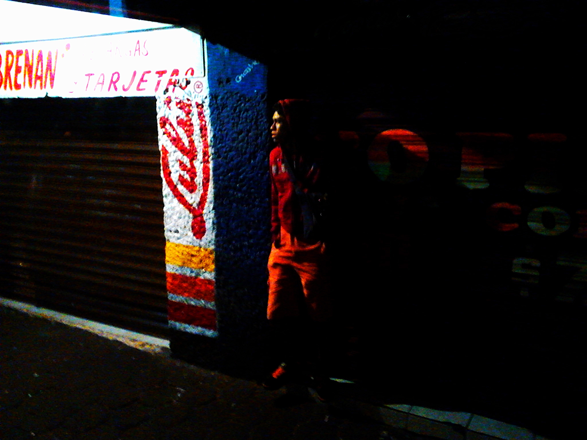 a dark street scene with a neon red and white umbrella
