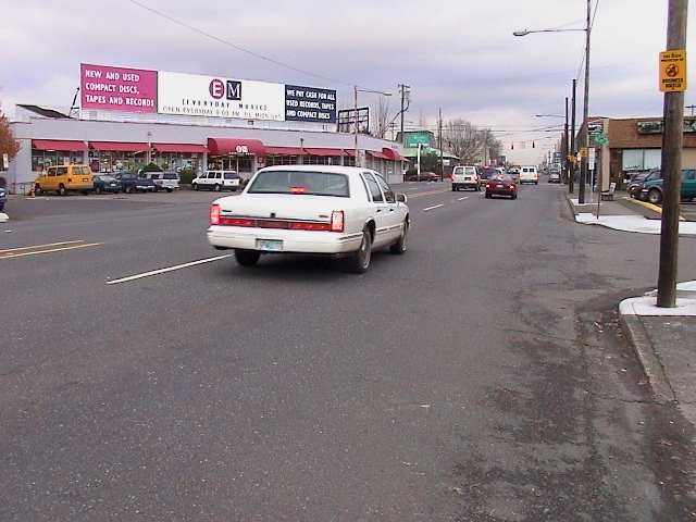 cars driving through an intersection near stores