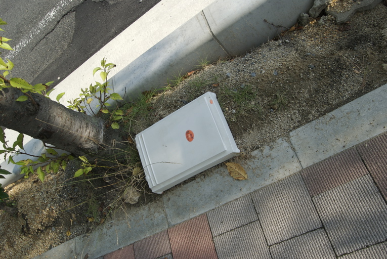 an old freezer laying on the ground near a street