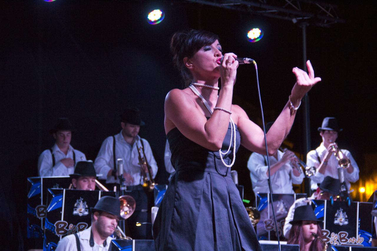 a woman is standing and singing while other musicians are playing